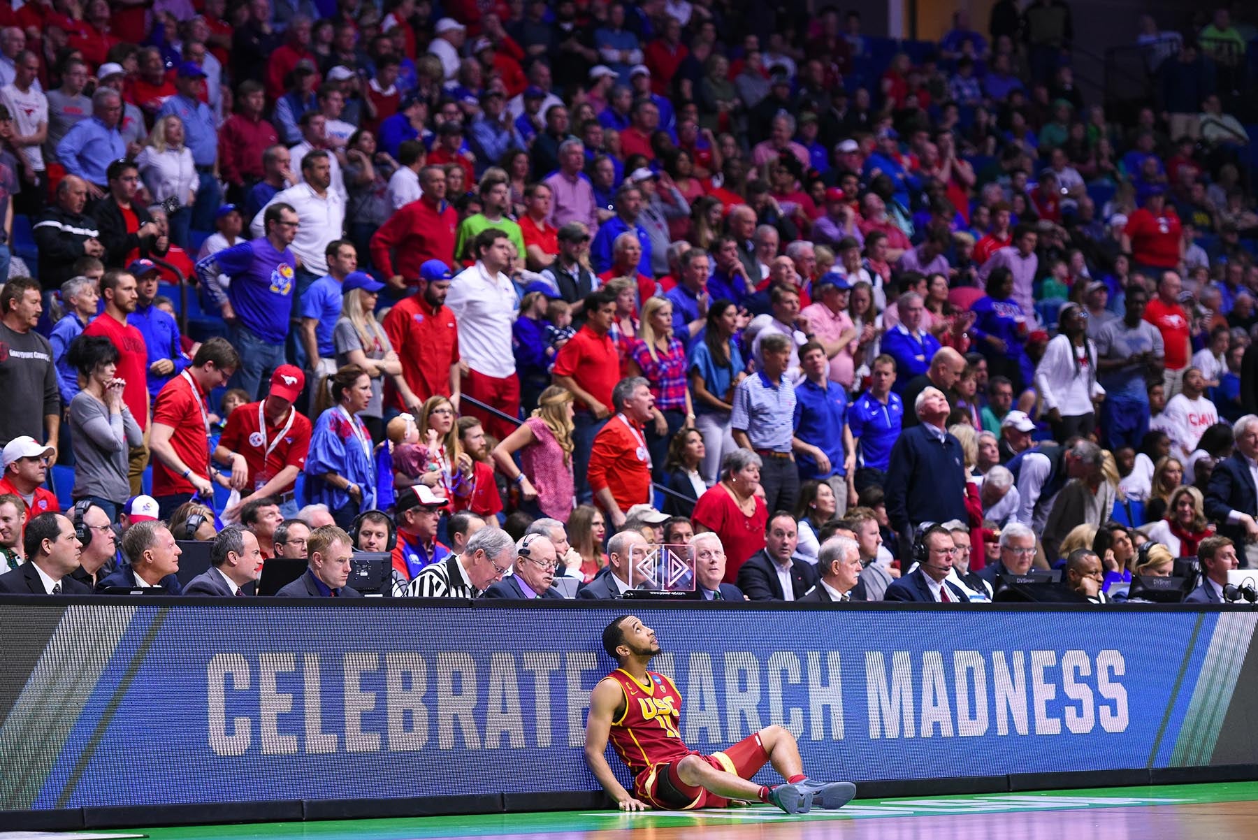 USC basketball player seated against backdrop of fans at SMU game