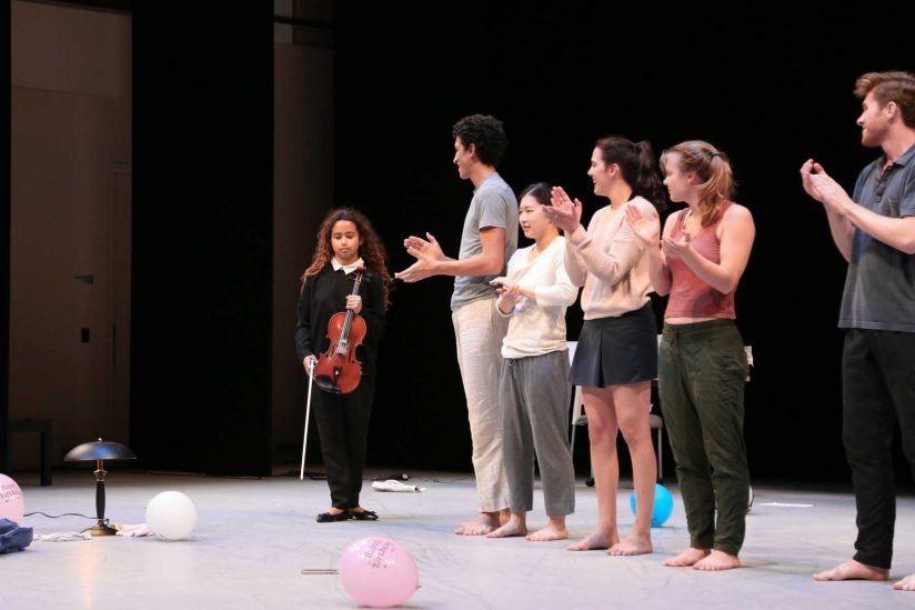 Mya Greene onstage with violin applauded by dancers