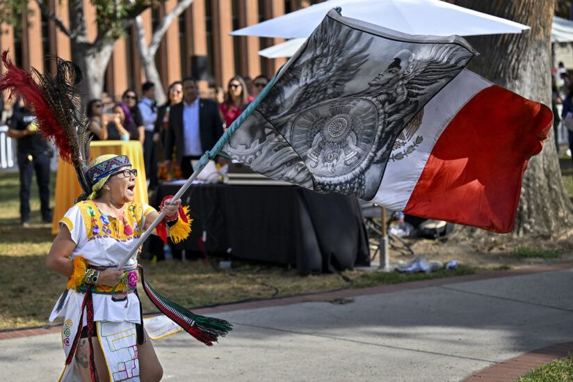 Indigenous person holding an Aztec/Mexico flag