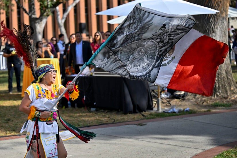 Indigenous person holding an Aztec/Mexico flag