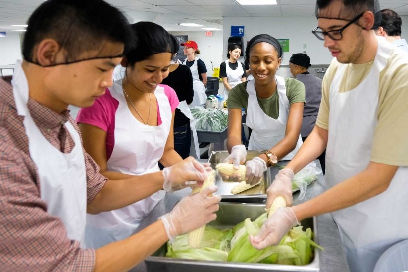 Group of four students shucking corn