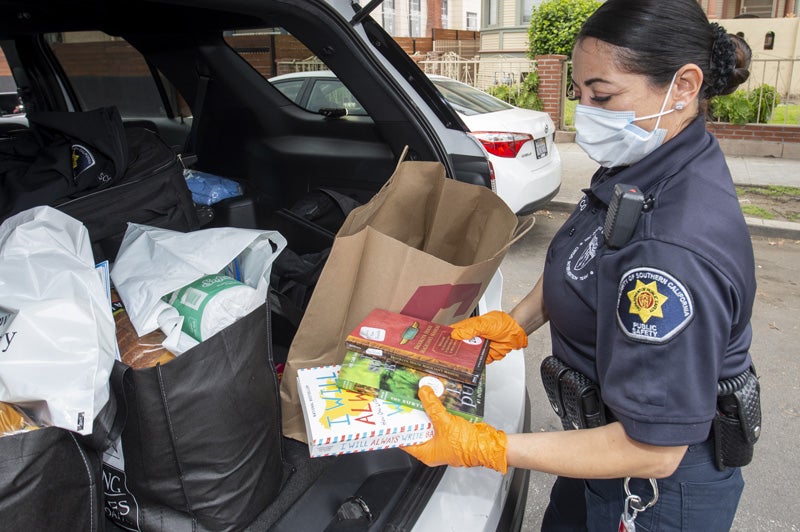 USC Department of Public Safety staff member distributes care packages of books, food and more to local families.