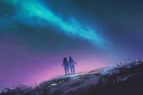 two people silhouetted against night sky and milky way galaxy