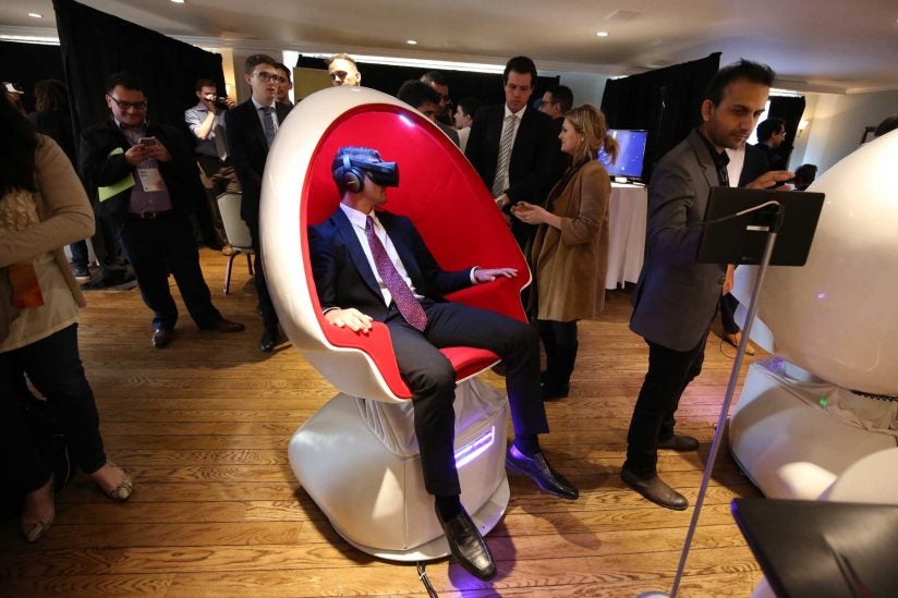 Man in suit and tie sitting in chair with VR headset