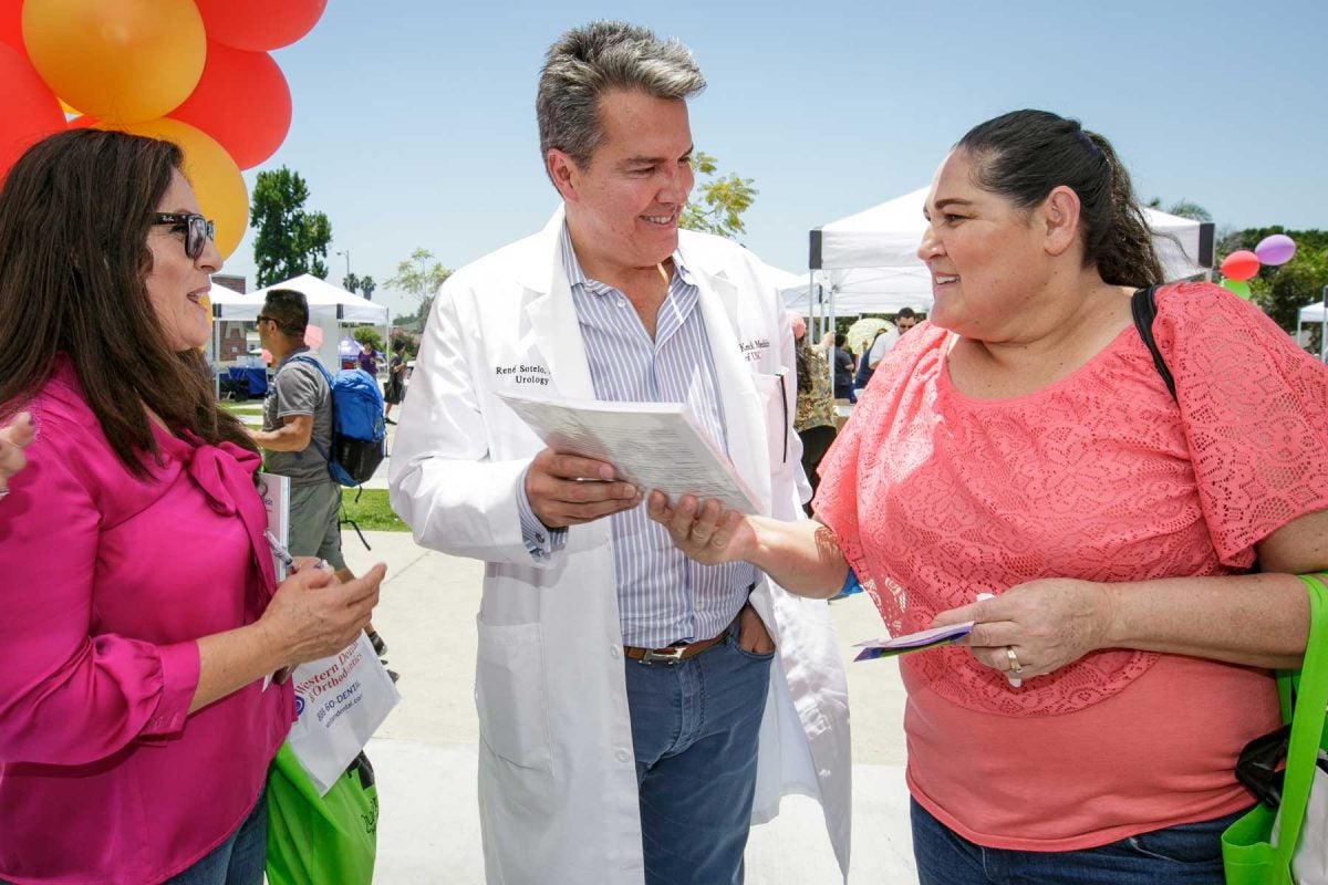 Rene Sotelo in white coat speaks to two sisters