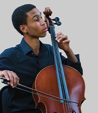 Quenton Blache in a black button-down shirt playing the cello
