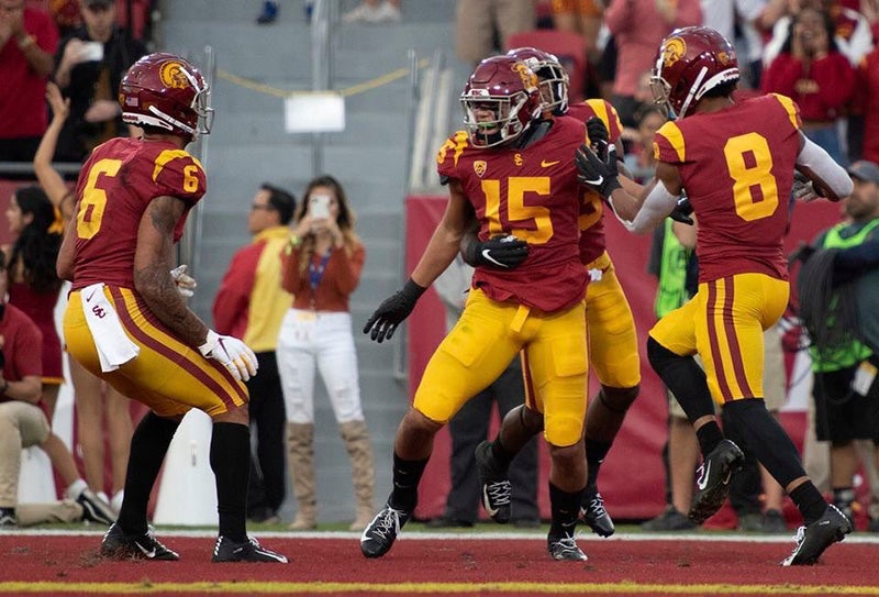 USC football players celebrate a touchdown in the end zone as Beverly Pham takes a photo on her cellphone in the background