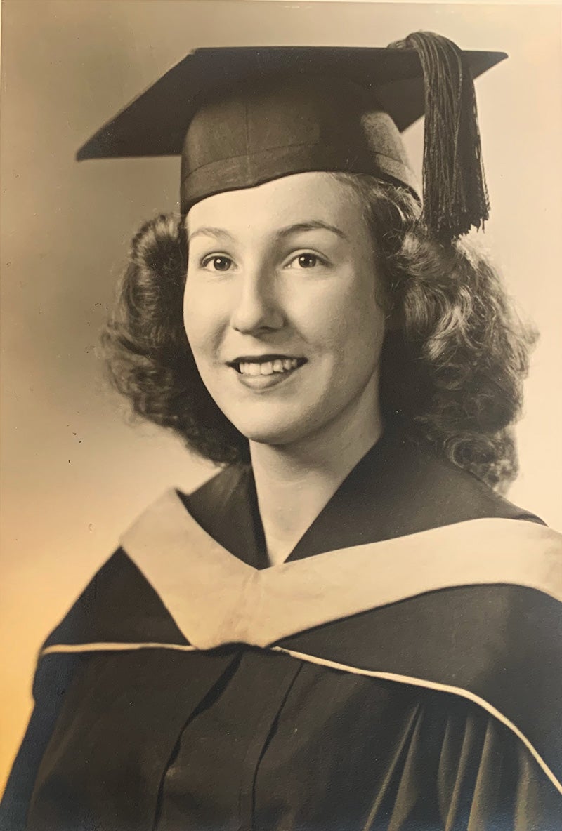 Black-and-white photo of Faye Demetriou in a graduation mortarboard and gown.