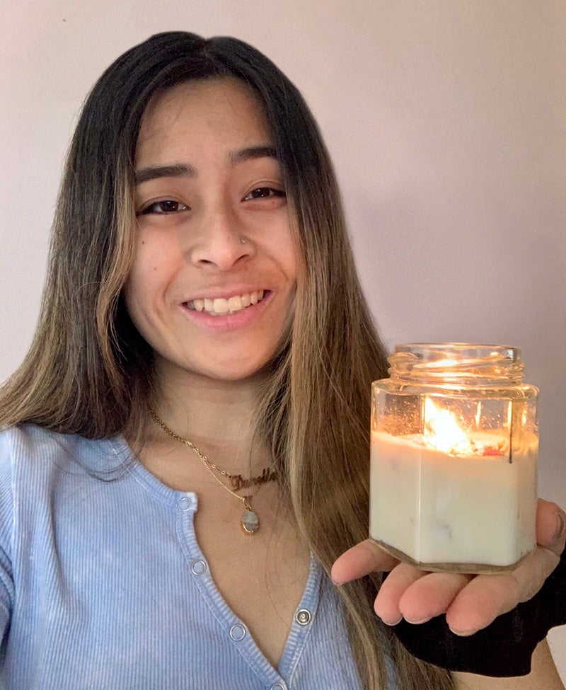 Danelle Go holding a lit candle in a glass jar