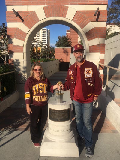 Melanie and Rob Cuddy in USC clothing at the entrance to USC’s John McKay Center.