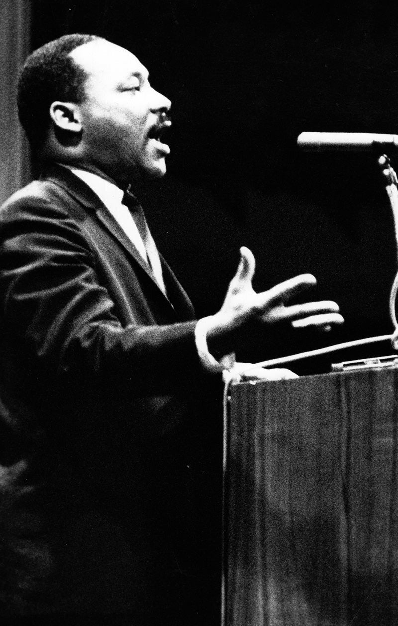Martin Luther King Jr. stands at a podium on the stage of Bovard Auditorium.
