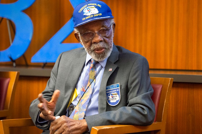 Ted Lumpkin in a suit and tie with a blue Tuskeegee Airmen Los Angeles Chapter hat and badge.