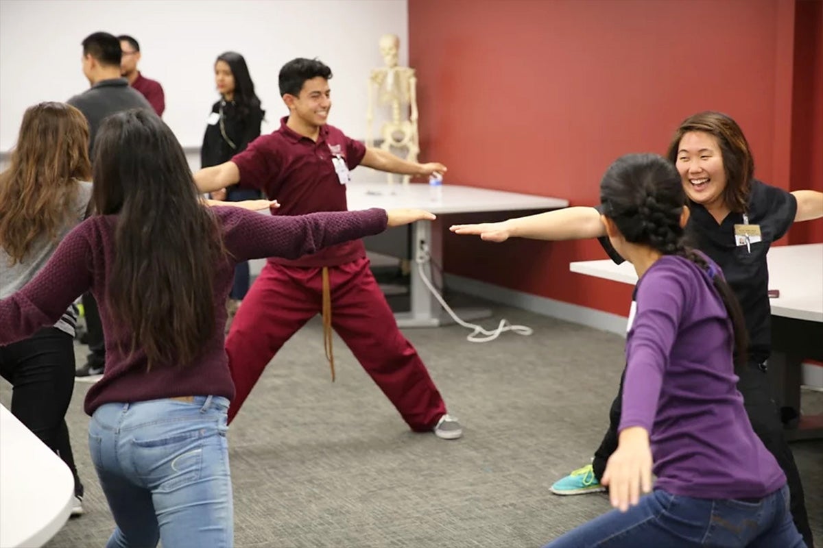 Students in the K-16 Pipeline program do stretches with health professionals in a conference room.