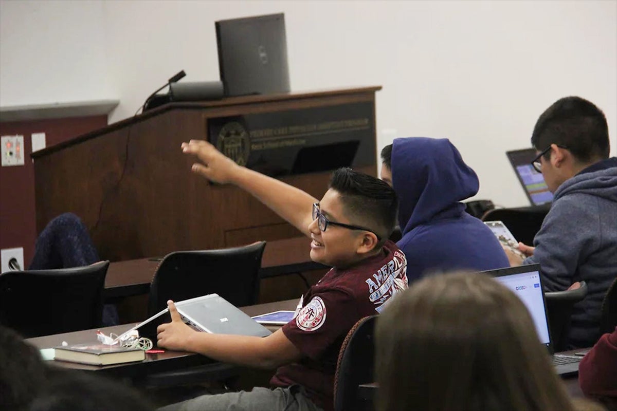A student raises his hand at a workshop in the LeAD and CrEW program.