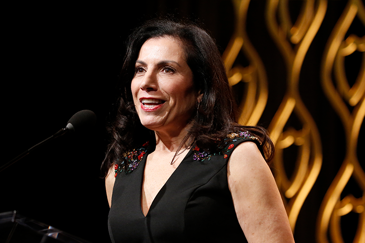 Brown-haired woman receives award and speaks into a mic