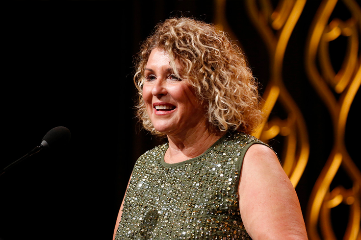 Blonde woman with curly hair receives award