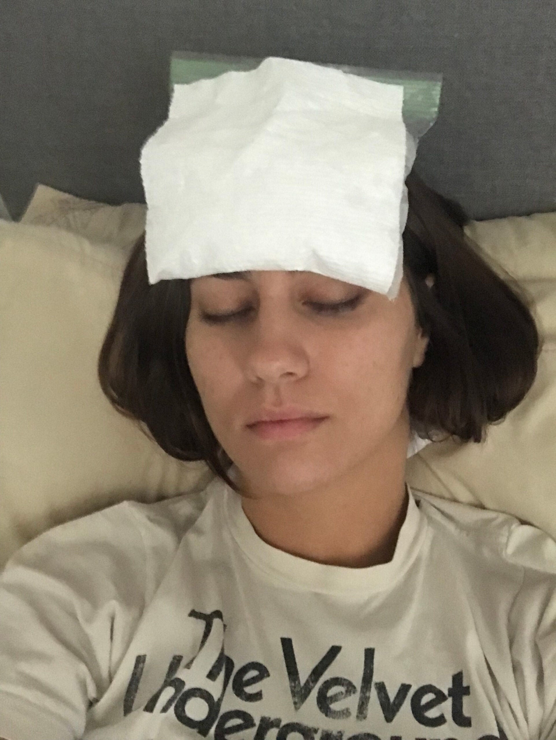 Woman holds an icepack on her forehead.