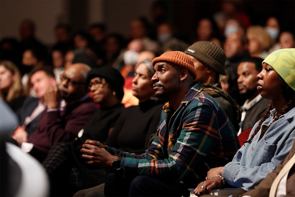 A man in an orange beanie and plaid shirt sitting in the audience at USC’s Bovard Auditorium.