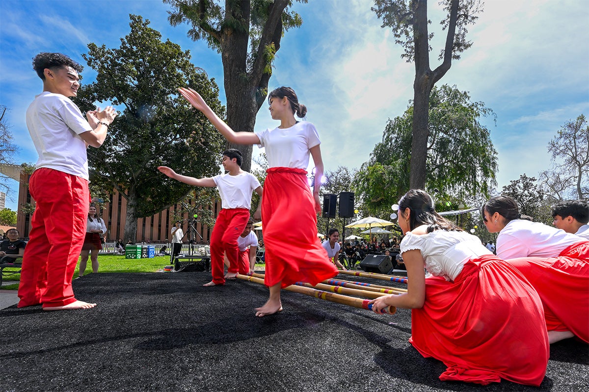 Members of USC Troy Philippines perform a traditional Filipino folk dance known as tinikling, involving bamboo poles.