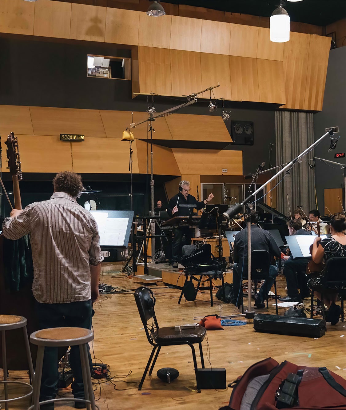 A man is conducting an orchestra on a sound stage.