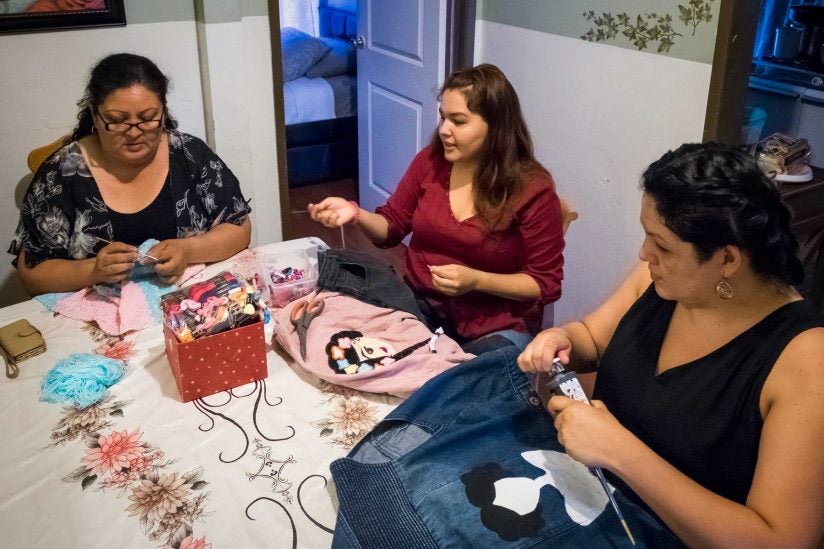 Ximena, mom and aunt sew together at table