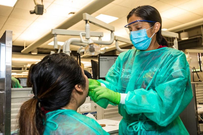 two students working together to practice dental techniques