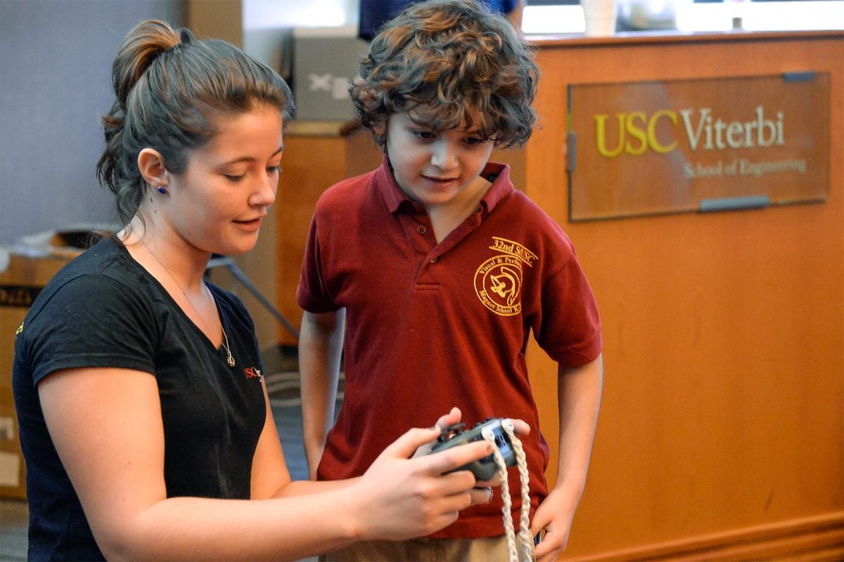 USC student Kiera Salvo shows Elias Rojano how to control the Vex U robot.