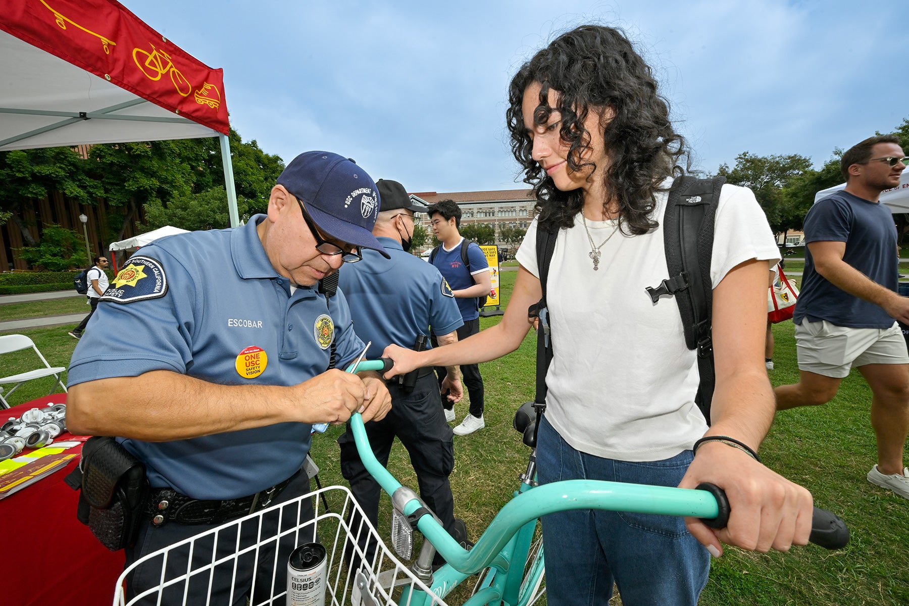 USC Safety Days: Javier Escobar installs USC-branded bike bell onto student Sofia Alayo’s bike