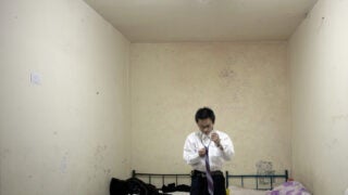 Worker in Beijing tries on suit and tie in windowless apartment