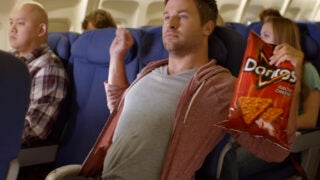 Doritos commercial of man holding chips while on an airplane