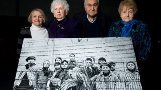 Survivors post with an iconic photo of them on Jan. 27 1945