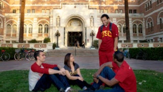 Four students chatting in front of Doheny Memorial Library