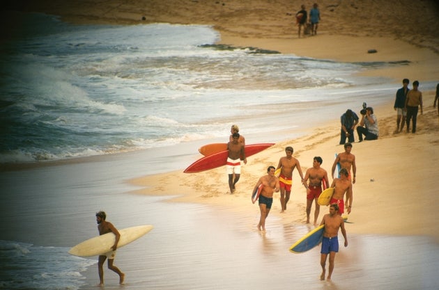 Various individuals on the beach with surfboards