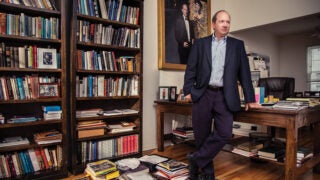 Man standing in a cluttered office wearing a suit