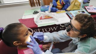 Little girl getting her teeth checked by USC dentistry student