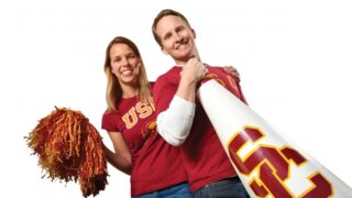 Two USC alumni holding a USC megaphone and pom poms