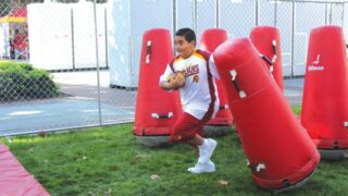 Little boy running through obstacle course with a football