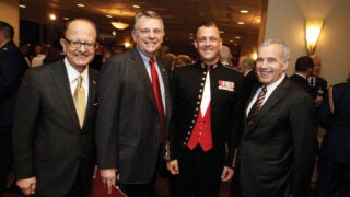 Four men standing side by side in formal wear posing for a picture