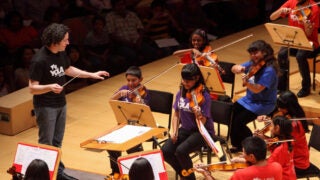 Conductor and teacher showing students how to play violin
