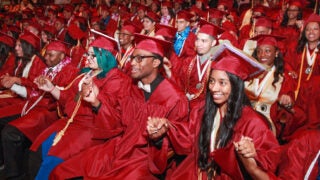 Graduates in caps and gowns holding hands