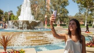 Student taking selfie in front of fountain