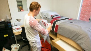 Student making his bed and unpacking his dorm room