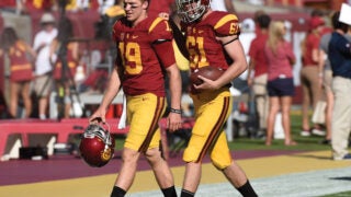 Blind long snapper Jake Olson walking on field in uniform with teammate