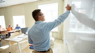 Male teacher writing on whiteboard