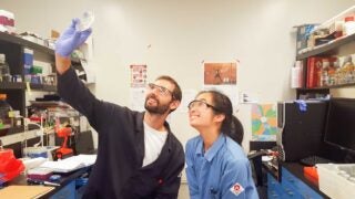 Two lab members studying specimen in a petri dish