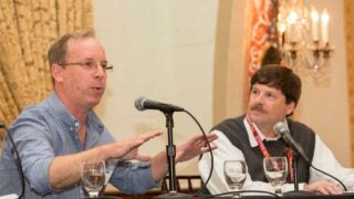 Two men speaking on a panel
