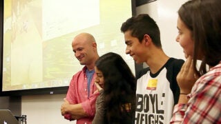 Professor and students looking at a laptop together