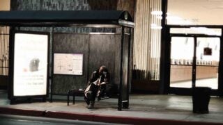 Person sitting at bus stop at night