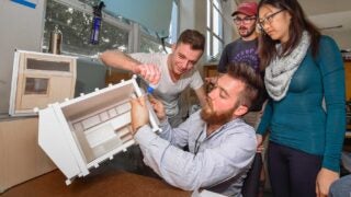 Students designing housing solutions using glue and cardboard