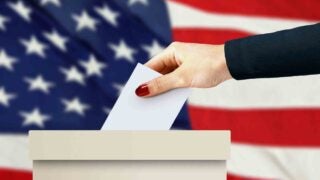 Person putting envelope in poll box